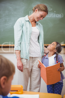 Cute pupil smiling to her teacher during class presentation