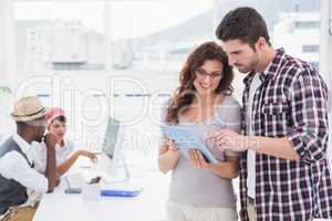 Coworkers standing and using tablet together