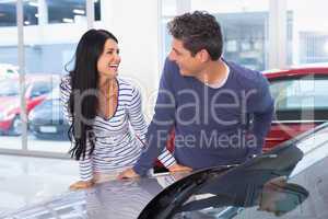 Smiling couple leaning on car