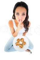 Pretty brunette eating plate of cookies