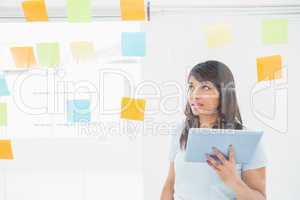 Businesswoman holding tablet and reading sticky notes