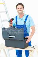 Happy carpenter removing drill machine from tool box