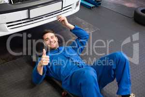 Mechanic lying and working under car