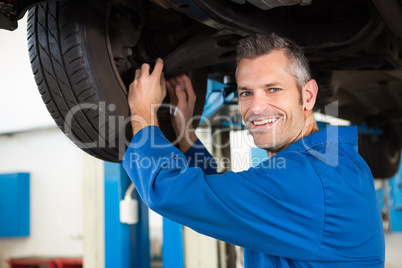 Smiling mechanic adjusting the tire