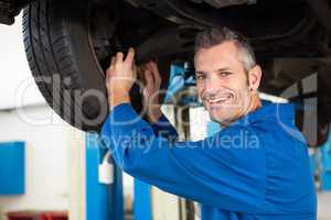 Smiling mechanic adjusting the tire