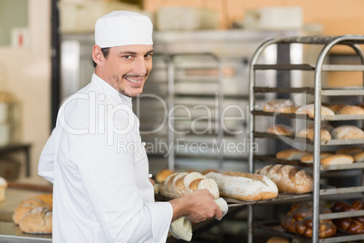 Smiling baker holding tray of bread