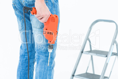 Worker holding drill in front of step ladder