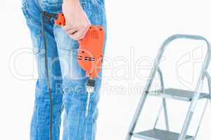 Worker holding drill in front of step ladder