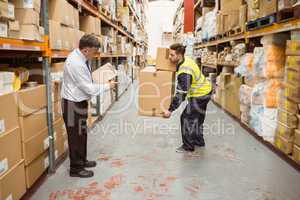 Manager watching worker carrying boxes