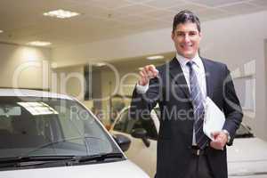 Businessman showing a car key while holding clipboard