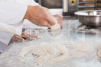 Close up of bakers kneading dough at counter