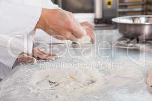 Close up of bakers kneading dough at counter