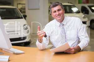 Smiling salesman holding car key and a document