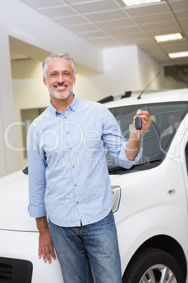 Male driver showing a key after bying a new car