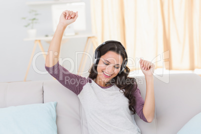 Pretty brunette listening to music on the couch