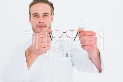 A optician showing glasses next to an eye test