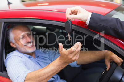 Smiling man driving a car while salesman his giving key