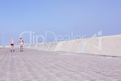 Fit couple rollerblading on the promenade