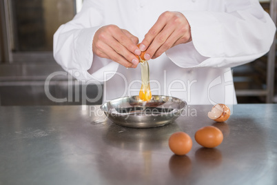 Close up of baker cracking an egg in bowl