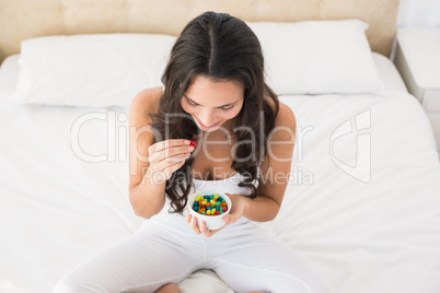 Pretty brunette eating candy in bed