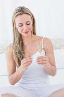 Smiling blonde woman with her pills on bed