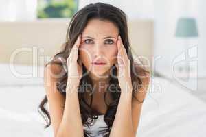 Worried brunette sitting on bed