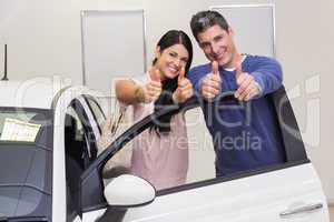 Smiling couple standing while giving thumbs up