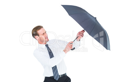Businessman holding umbrella to protect himself