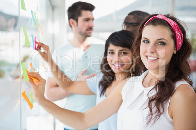 Smiling coworkers pointing sticky notes