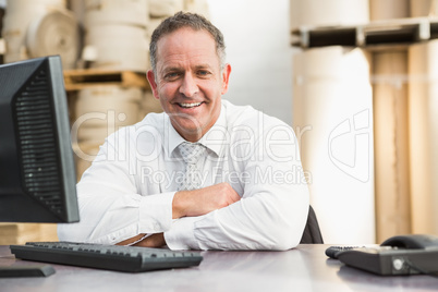 Smiling manager with arms crossed sitting at desk