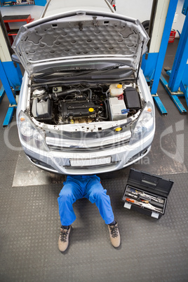 Mechanic lying and working under car