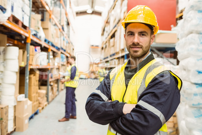 Smiling worker wearing yellow vest with arms crossed