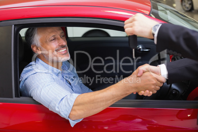 Businessman giving car key while shaking a customer hand