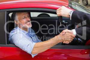 Businessman giving car key while shaking a customer hand