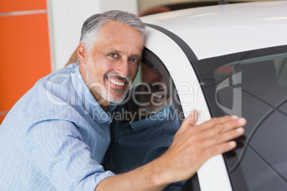 Smiling man hugging a white car