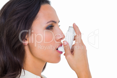 Asthmatic brunette using her inhaler