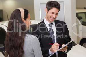Salesperson showing clipboard to sign to customer