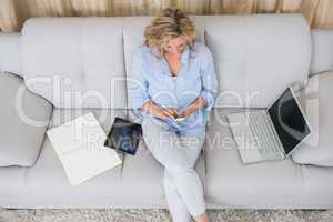 Blonde sitting on couch using her smartphone