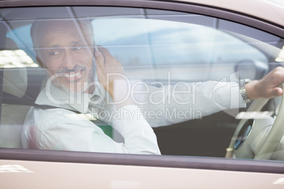 Smiling businessman on the phone in his car