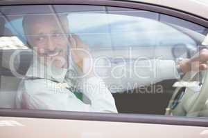 Smiling businessman on the phone in his car
