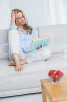 Smiling blonde reading a book on couch
