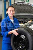 Mechanic smiling at the camera holding tire