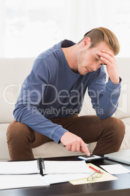 Concentrated man using calculator counting his bills