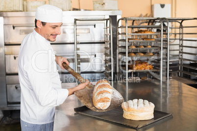 Happy baker taking out fresh loaf