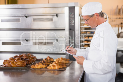 Focused baker writing on clipboard