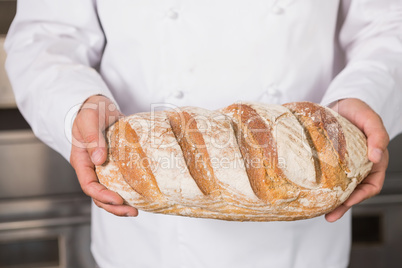 Baker showing freshly baked loaf