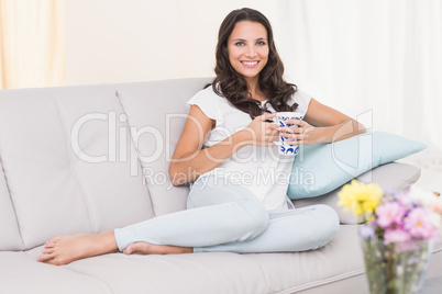 Pretty brunette having coffee on couch