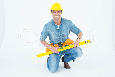 Worker using spirit level while kneeling over white background