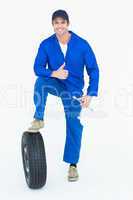 Mechanic with tire and wheel wrenches gesturing thumbs up