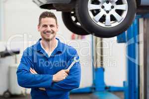 Mechanic smiling at the camera holding tool